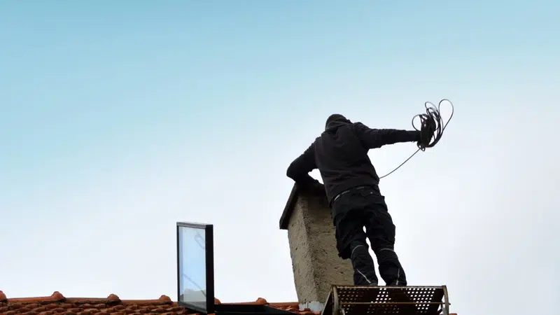 Personne nettoyant une cheminée sur un toit